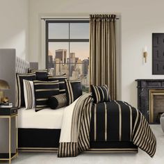 a bedroom with black and white bedding in front of a cityscape window