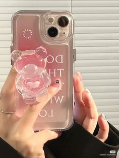 a person holding up a clear phone case with a pink teddy bear in the middle