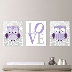 two purple owls are hanging on the wall above a crib with a teddy bear