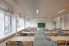 an empty classroom with wooden desks and chairs