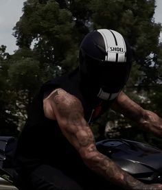 a man riding on the back of a motorcycle wearing a helmet and holding onto his bike