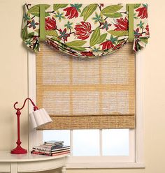 a window with roman shades and flowered valance on the top, next to a lamp