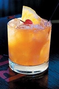 an orange drink sitting on top of a wooden table