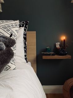 a teddy bear sitting on top of a bed next to a night stand with a lit candle