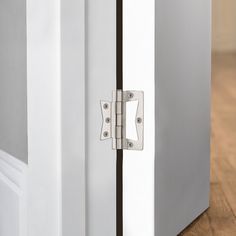 a close up of a door handle on a white refrigerator with wood flooring in the background