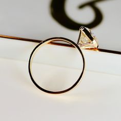 a diamond ring sitting on top of a piece of paper with the letter g in it