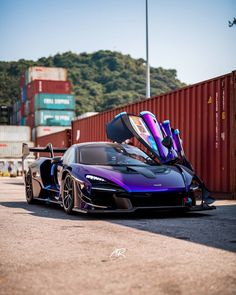 a purple and blue sports car parked in front of a shipping container