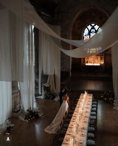 a bride and groom standing at the end of a long table with candles on it