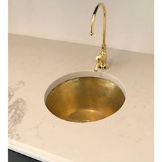 a white counter top with a gold sink and faucet on the left side