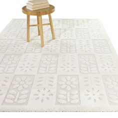 a table with books on top of it in front of a white rug and chair