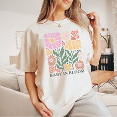 "Celebrate the journey of motherhood with our Baby In Bloom t-shirt! This adorable shirt is the perfect gift for your pregnant daughter or any expecting mom. With its charming design, it makes for a heartwarming pregnancy reveal or baby announcement idea. Let your loved one proudly display their blossoming journey into motherhood with this thoughtful and stylish shirt. Our Garment-Dyed Heavyweight t-shirts are relaxed and UNISEX sized.  A great go to shirt for those who appreciate a structured f Cute Maternity T-shirt With Graphic Print, Cute Maternity Graphic Print T-shirt, Cute Maternity Cotton T-shirt, Maternity Graphic Tee With Short Sleeve, Maternity T-shirt With Graphic Print And Relaxed Fit, Maternity Family Matching T-shirt With Graphic Print, Maternity Summer T-shirt Crew Neck, Summer Maternity T-shirt With Crew Neck, White Graphic Maternity T-shirt