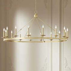 a gold chandelier with candles hanging from it's center and two walls in the background