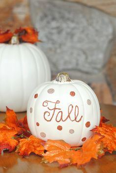 two white pumpkins with the word fall painted on them