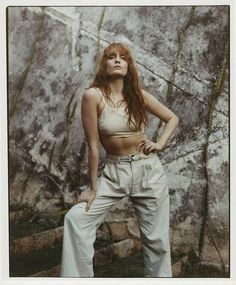 a woman standing in front of a rock wall with her hands on her hips and looking up