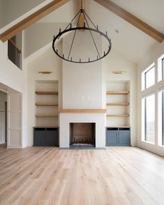 an empty living room with wood floors and open shelves on either side of the fireplace