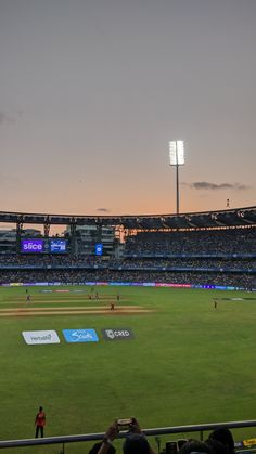 an empty baseball stadium with people watching the game at sunset or dawn, as seen from the stands