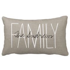 a pillow with the word family on it in black and white ink, sitting on top of a beige linen cushion