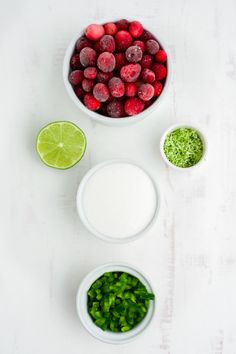 three bowls filled with raspberries, limes and other ingredients on a white surface