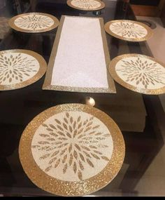 the table is decorated with gold and white plates on it's glass top, along with other decorative items