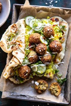 some food is sitting on top of a paper bag and next to another plate with meatballs