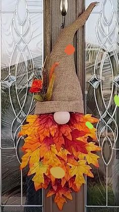 a scarecrow door hanger decorated with fall leaves and a burluck hat