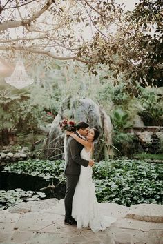 a bride and groom kissing in front of a pond