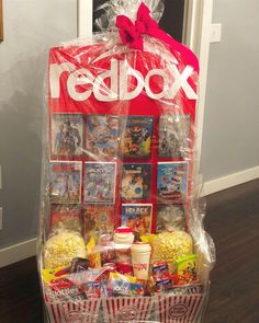 a red box filled with movies and snacks on top of a hard wood floor next to a door