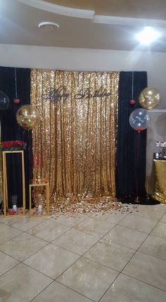 a party room with gold sequins and black drapes on the door, balloons in the air