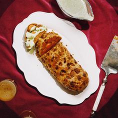 a white plate topped with food on top of a red table cloth next to silverware