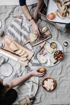 several people are sitting at a picnic table with food on the plates and serving utensils