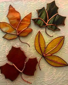 four stained glass leaves on a white doily