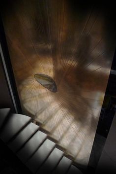 the sun is shining through an open window in a room that has stairs and light coming from it