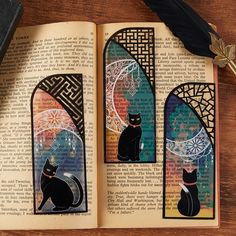 an open book with two black cats sitting on top of it next to a feather