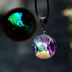 a necklace with a glass ball hanging from it's side next to an image of the moon