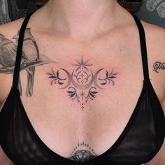 a woman with tattoos on her chest wearing a black bra