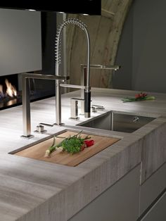 a kitchen counter with a cutting board on it next to a sink and stove in the background