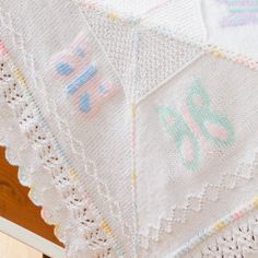 a crocheted baby blanket is laying on top of a wooden floor with the word love written across it