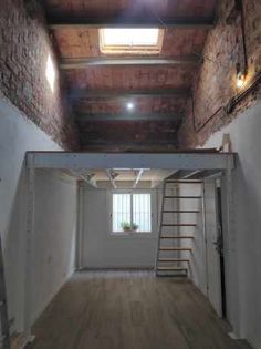 an empty room with ladders leading up to the window and skylight above it