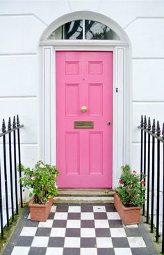 a pink door with two potted plants next to it on a black and white checkered floor