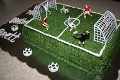 a cake made to look like a soccer field with people playing on it and the grass is green