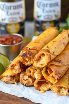 several tortillas stacked on top of each other with salsa and limes in the background