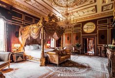 an ornate bedroom with four poster bed, chandelier and two chairs in it