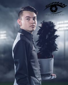 a man in uniform holding a black feathered hat and posing for a photo with stadium lights behind him