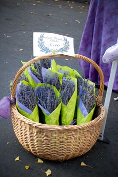 a basket filled with purple flowers sitting on top of a street next to a sign