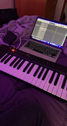 a laptop computer sitting on top of an electronic keyboard next to a keyboard mouse and headphones