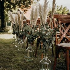 there are many chairs and vases with flowers in them on the grass near each other