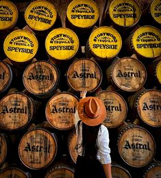 a woman wearing a hat standing in front of wooden barrels