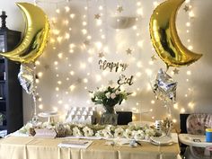 a table topped with balloons and flowers next to a wall covered in stars, moon shaped balloons