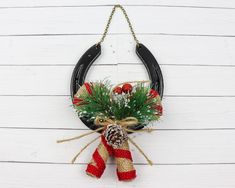 a christmas wreath hanging on the side of a white wooden wall with black horseshoes