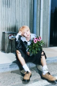 a person sitting on the ground with flowers in their hands